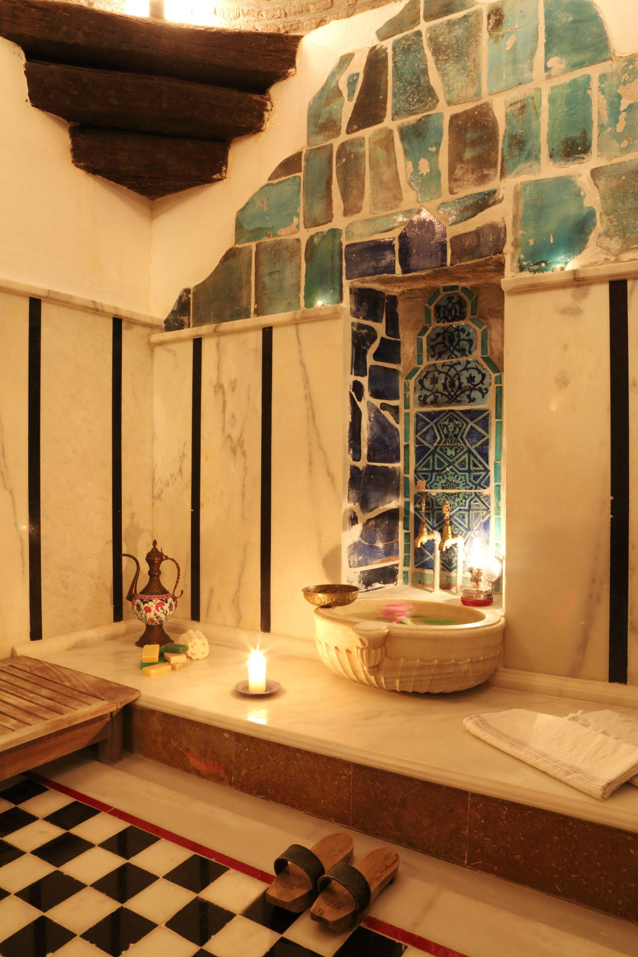 Turkuaz çinili, mermer kurnalı, mum ışığında bir hamam